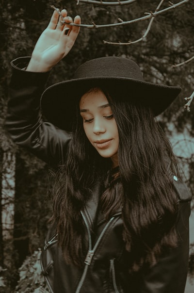 A woman dressed in a black leather jacket and a black hat
